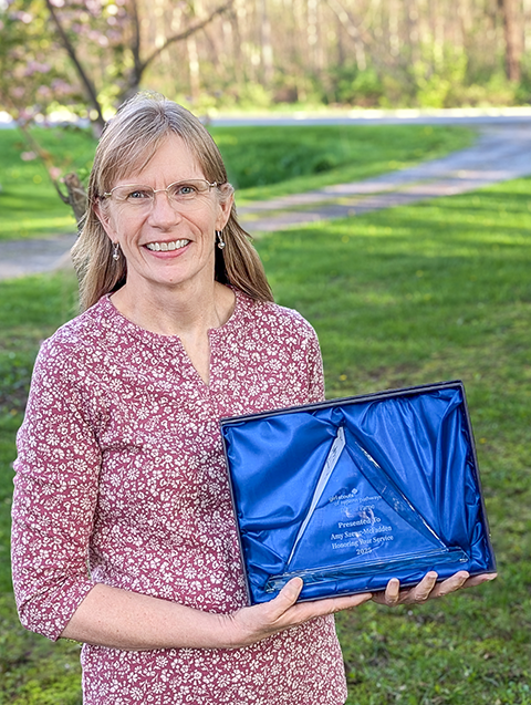 photo of diane bootie and grace nassar, diane is holding the hall of fame trophy, a glass triangle shape